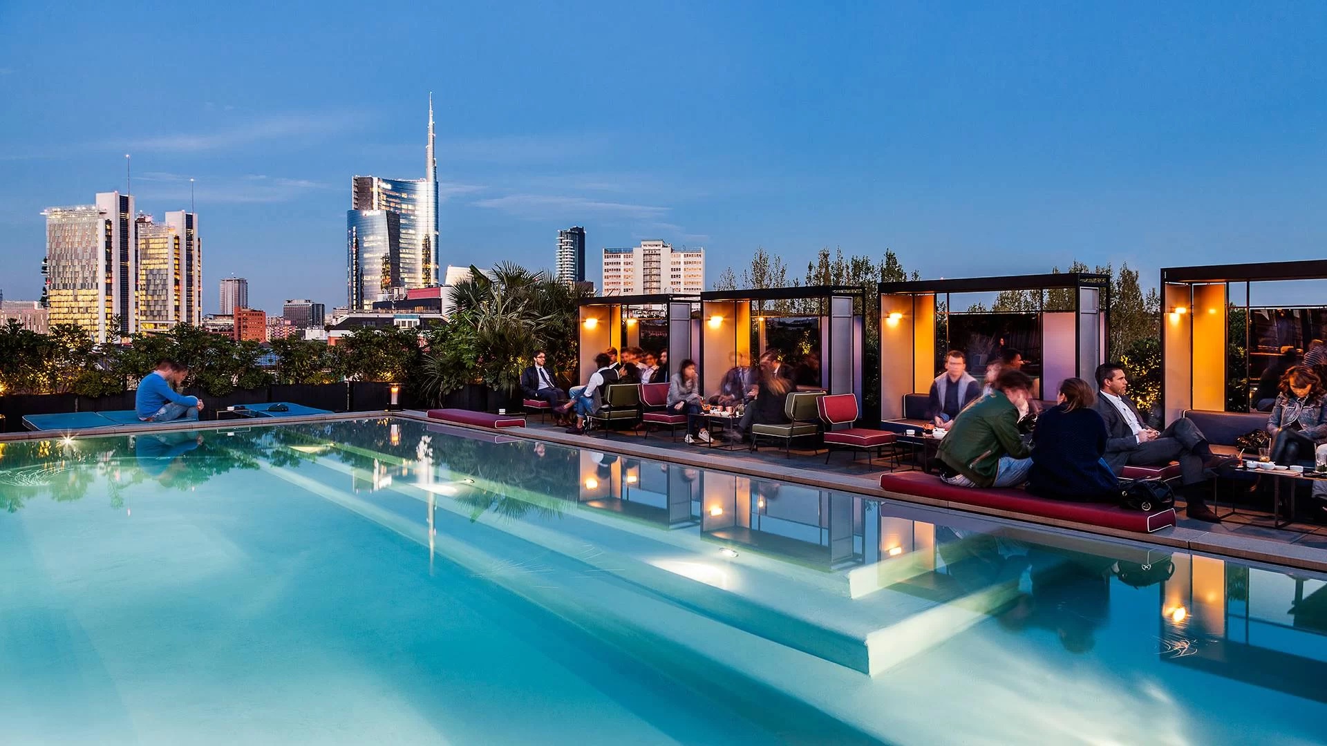 People in meetings by a pool looking the Milan skyline